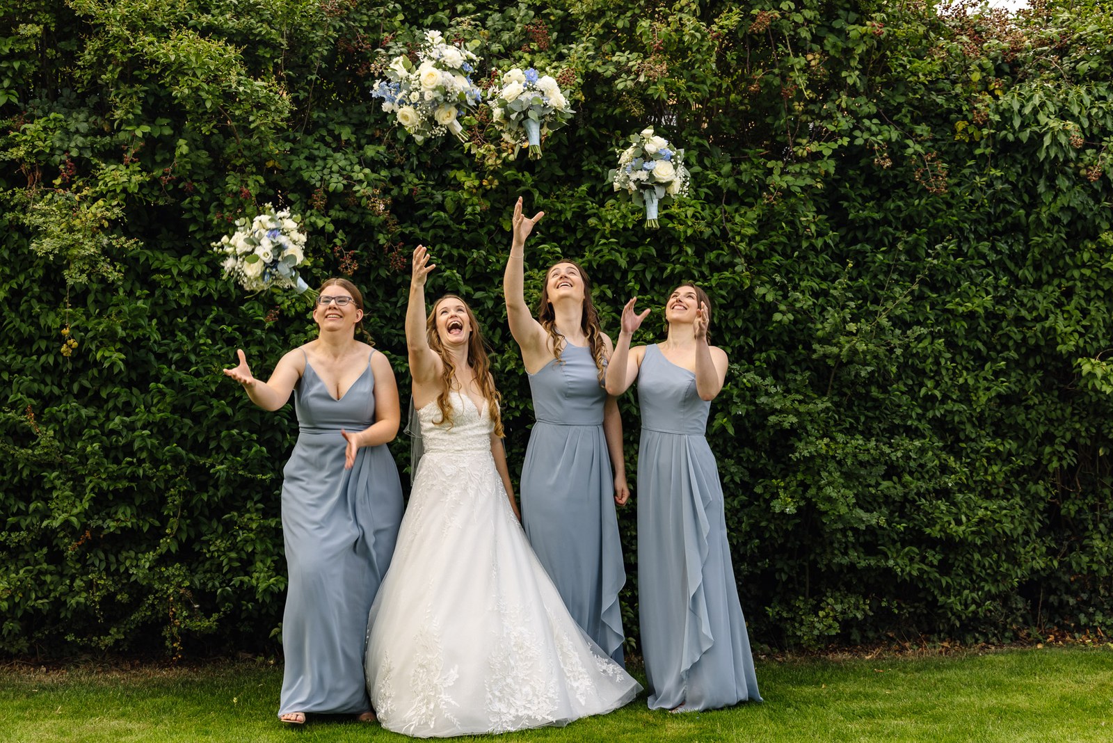 Bride and bridesmaids tossing their bouquets in the air at Winters Tale Country Barn