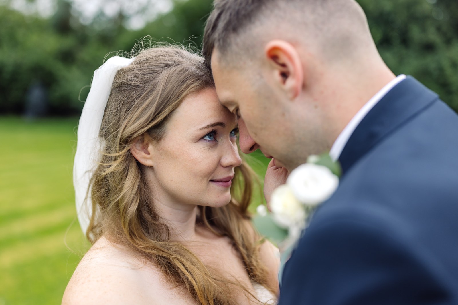 Close-up of the couple touching foreheads as the groom kisses her hand