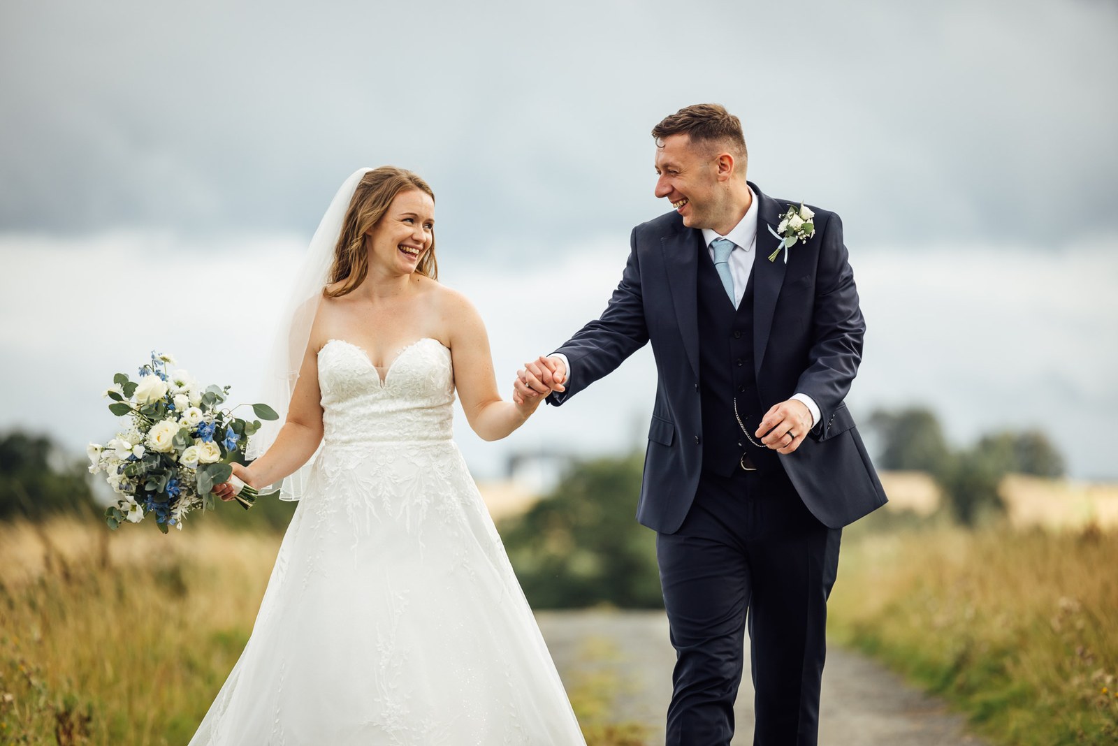 The newlyweds walking a winding country path through open fields