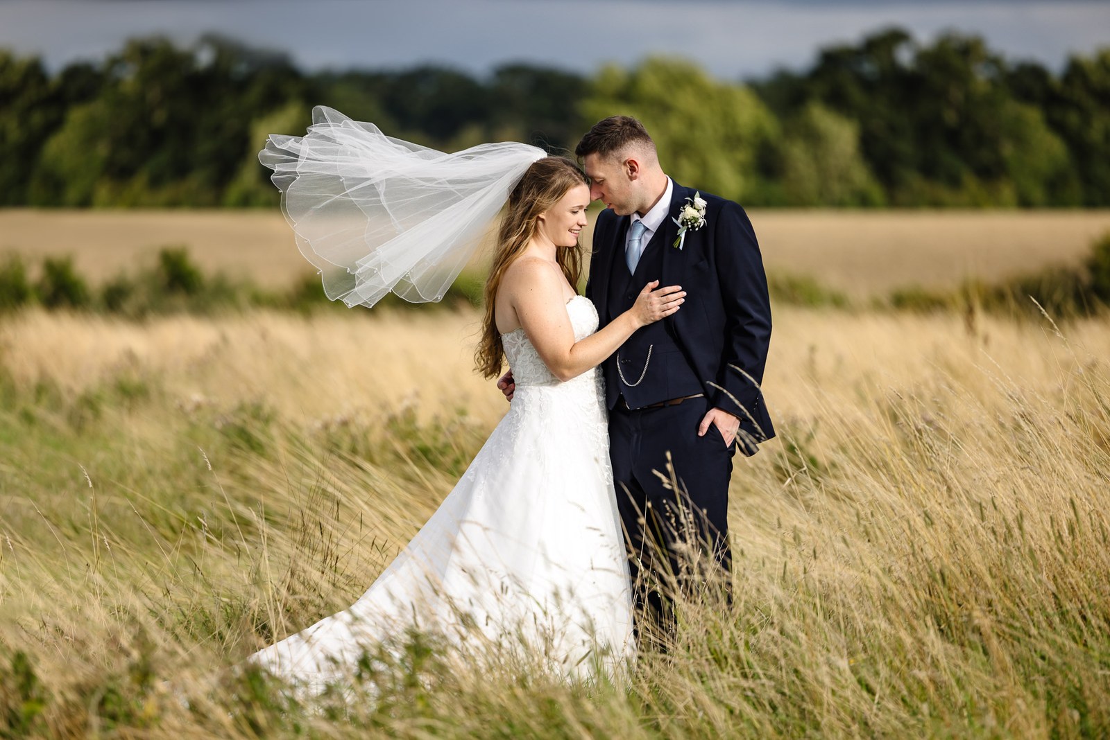 Bride and groom embracing in the meadow grass at Winters Tale Country Barn