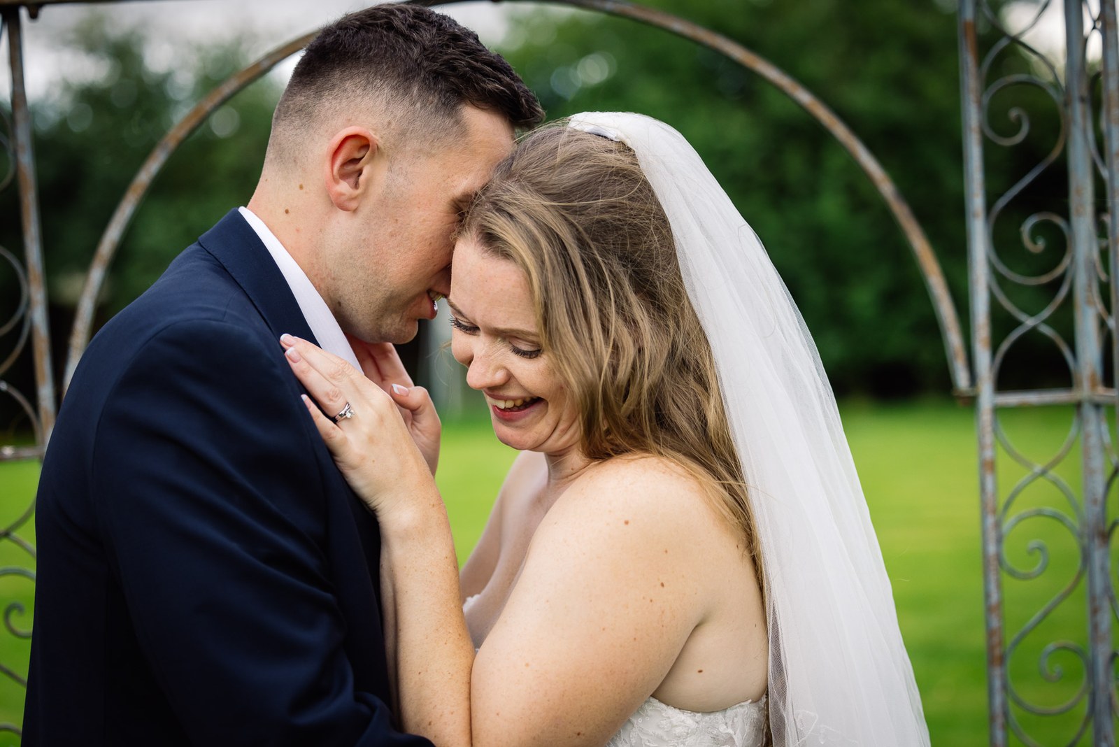 Close-up of the couple embracing beneath a wrought-iron garden arch