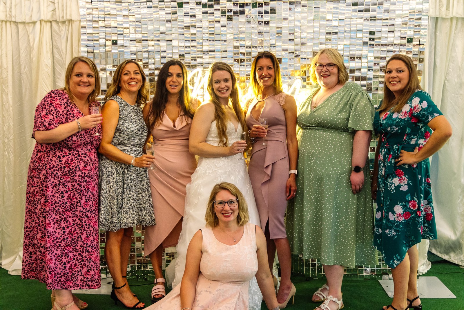 Bride posing with a group of guests before a sequinned backdrop
