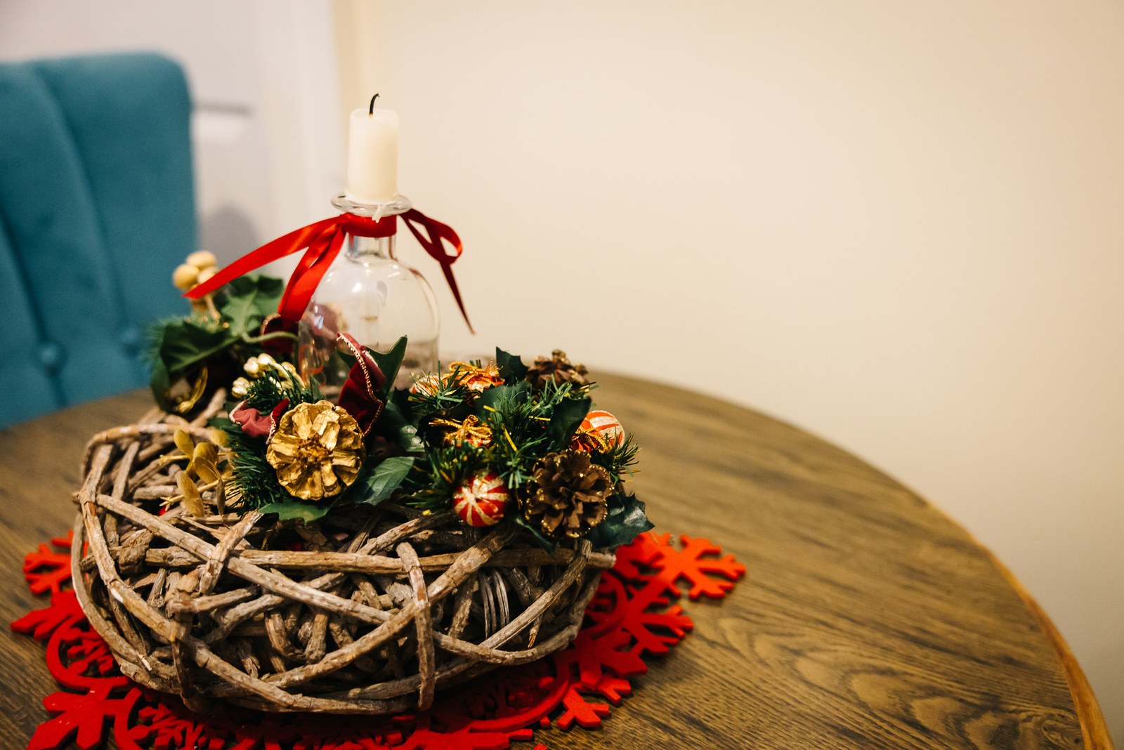 A rustic twig wreath centrepiece with a candle and red ribbon