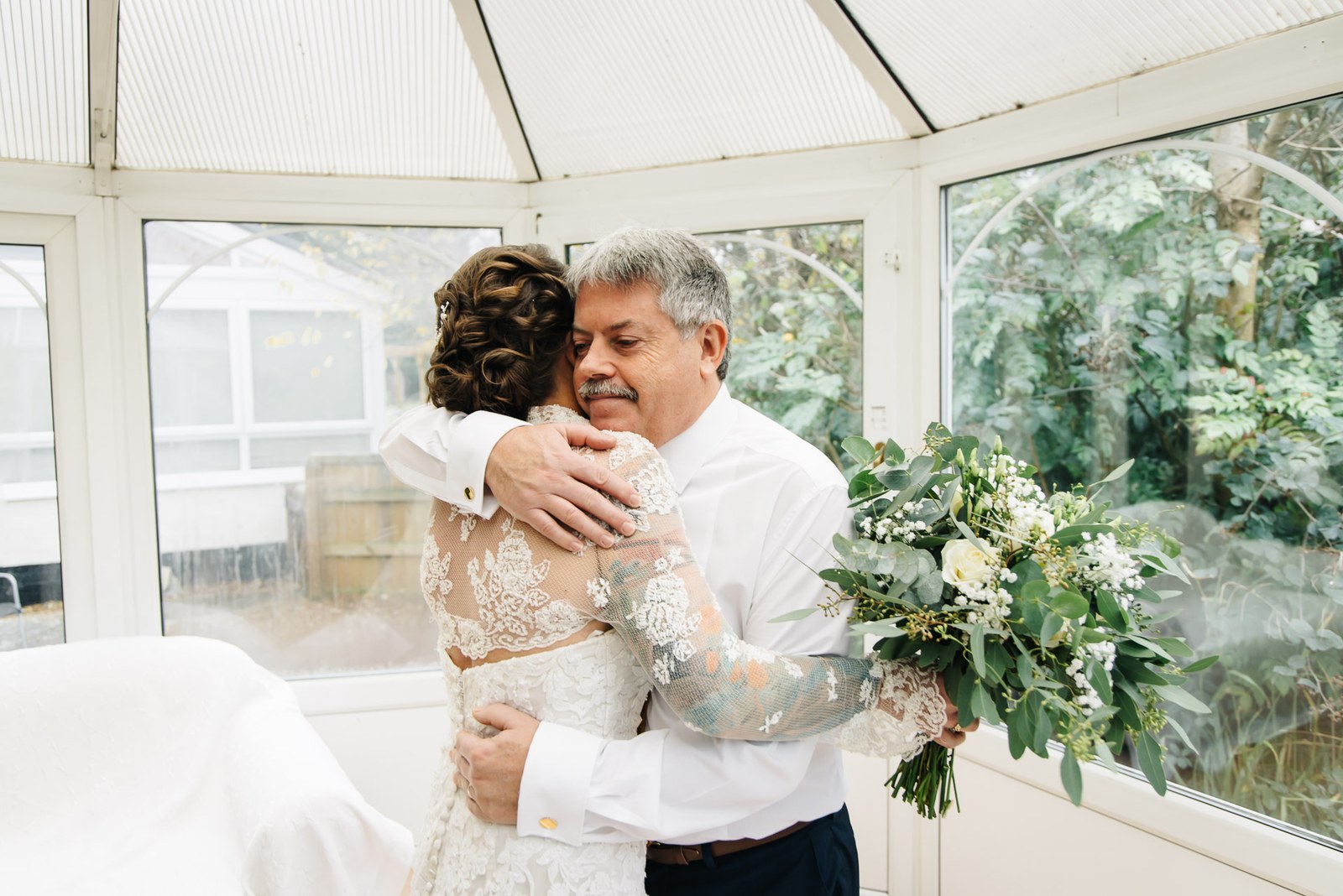 Bride embracing her father in the conservatory
