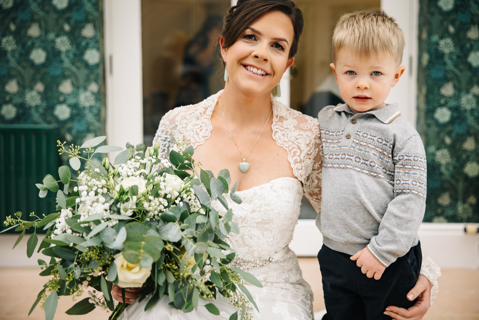 Bride standing with a young page boy while holding her bouquet