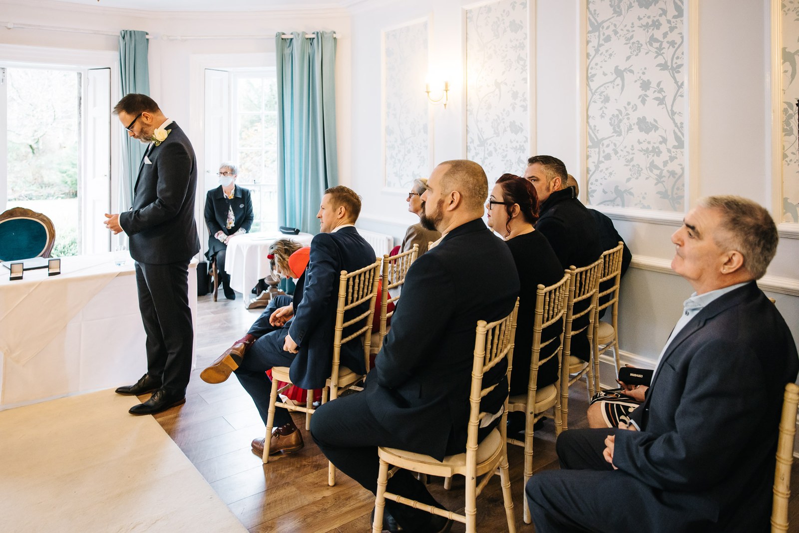 The groom waiting with seated guests in the Woodlands Lodge Hotel ceremony room