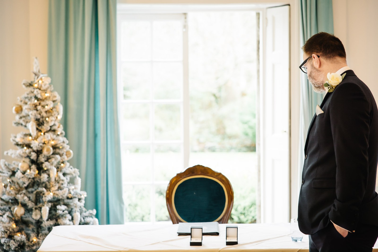 The groom beside the registrar's table by a flocked Christmas tree