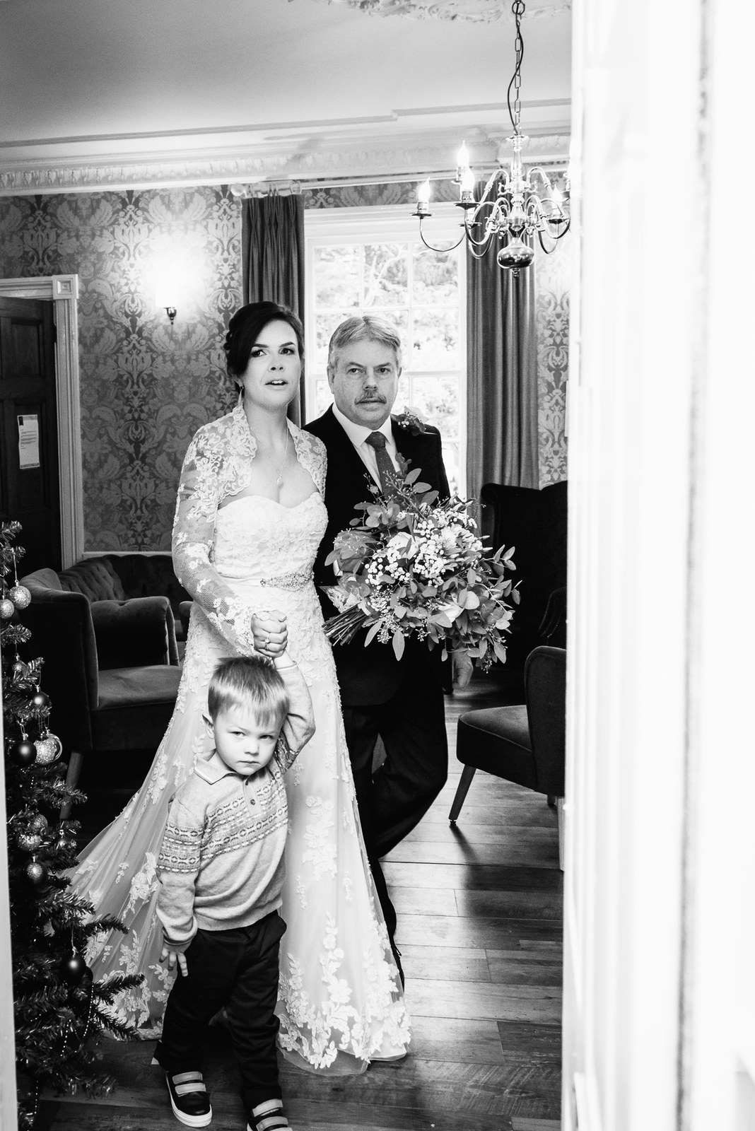 Black and white shot of the bride entering with her father, holding the page boy's hand