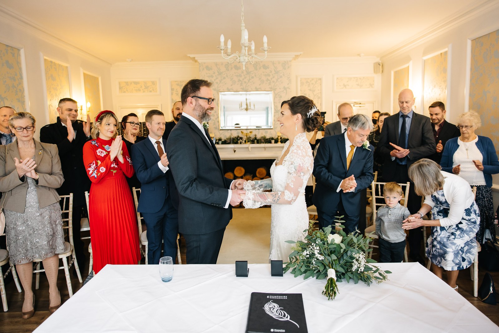 The couple taking each other's hands at the front as guests applaud