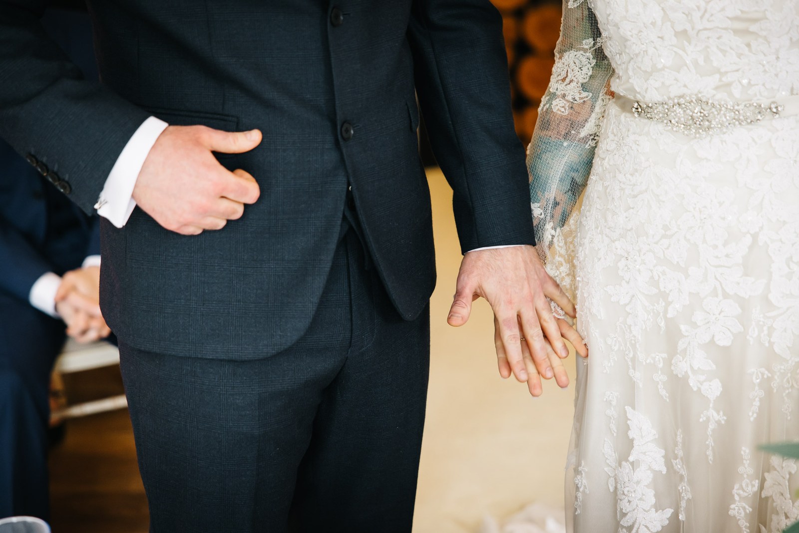 Close-up of the couple's hands brushing at their sides and the bride's diamante belt