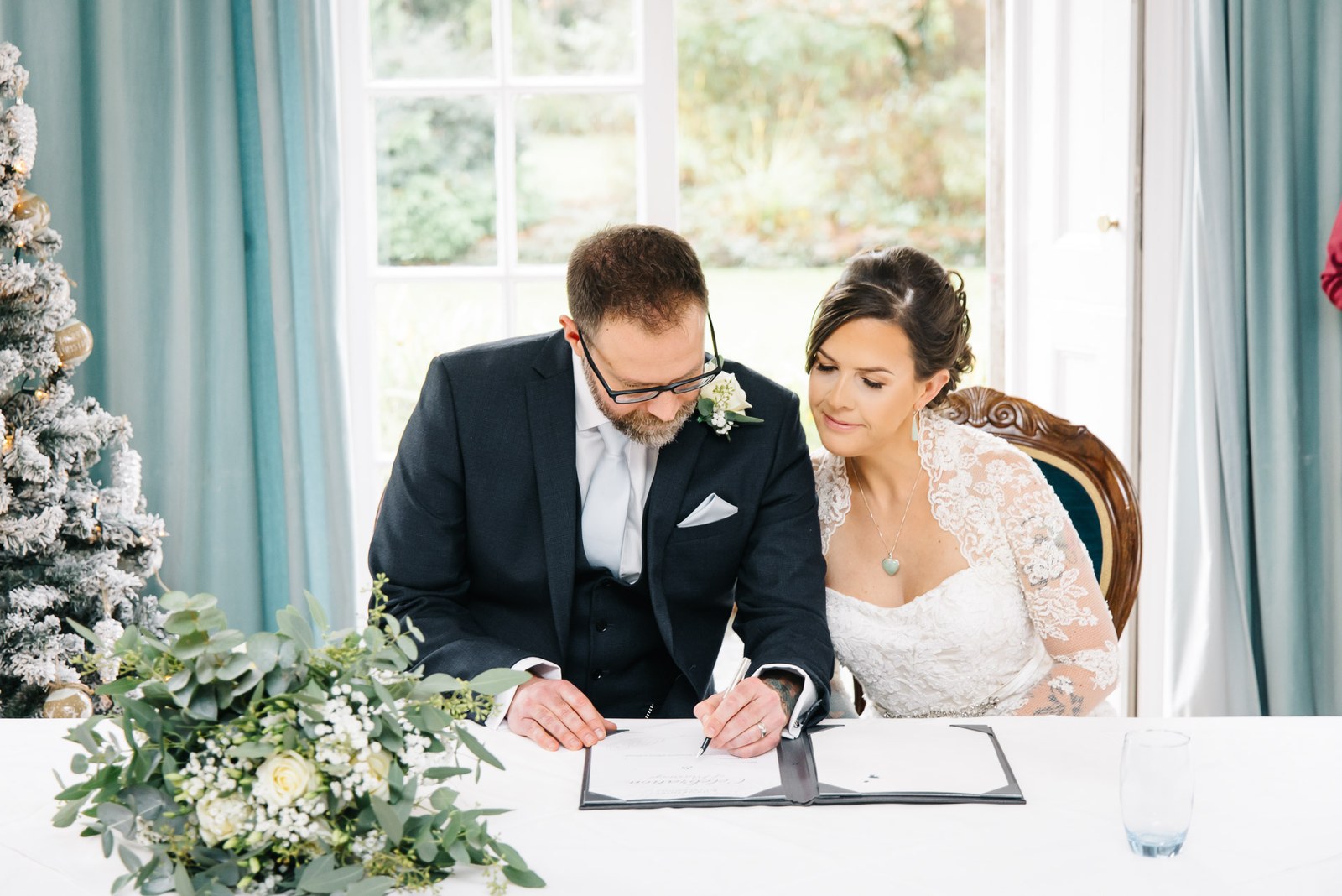 The couple signing the register beside a flocked Christmas tree