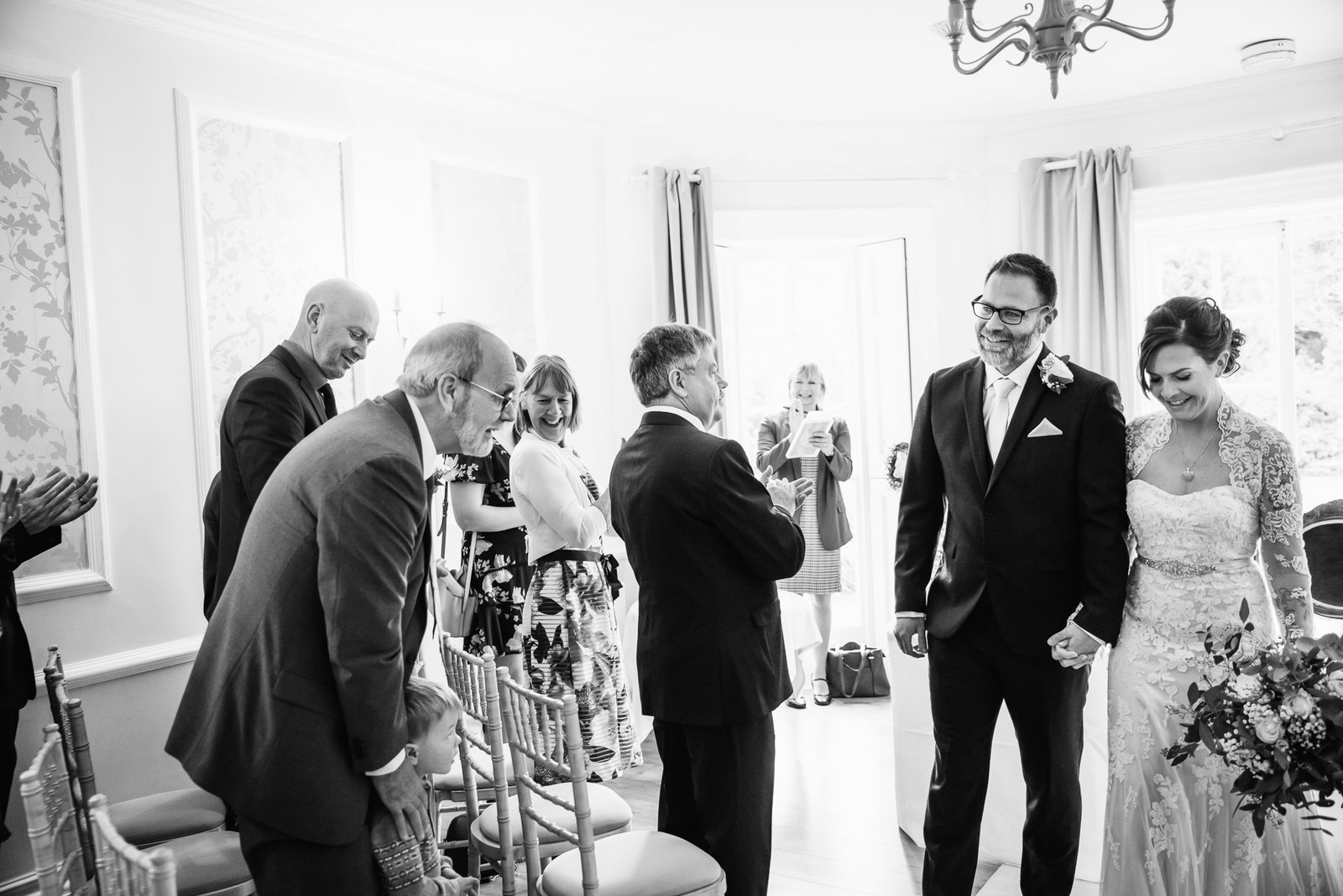 Black and white moment of guests congratulating the newlyweds