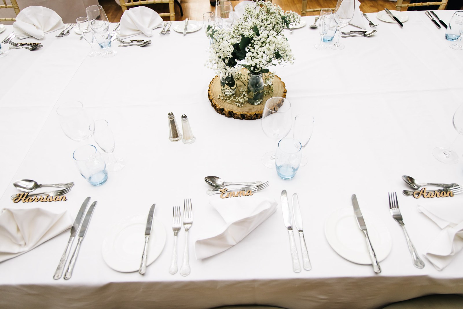 A round table setting with a gypsophila centrepiece on a wood slice