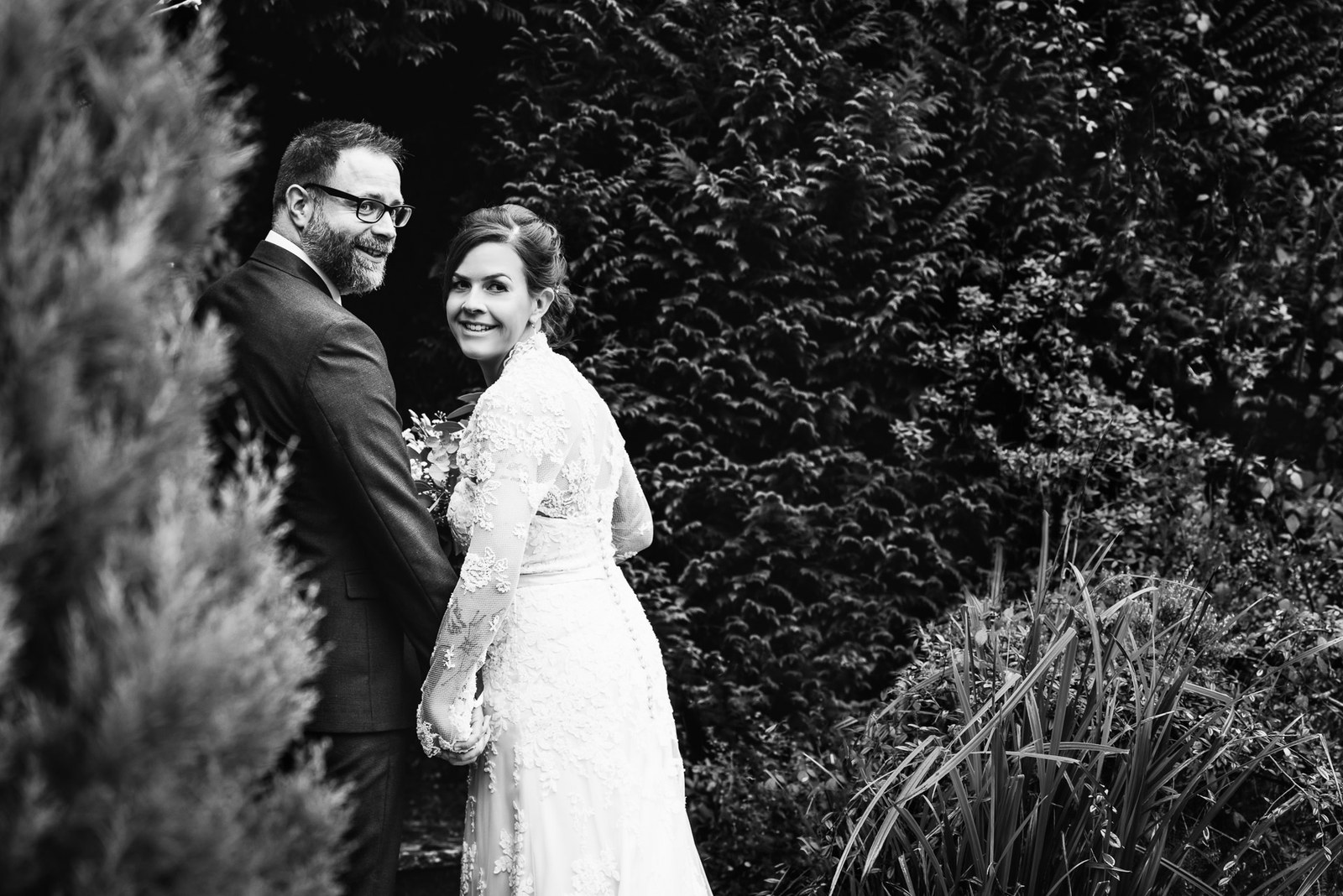 Black and white portrait of the couple among the garden greenery