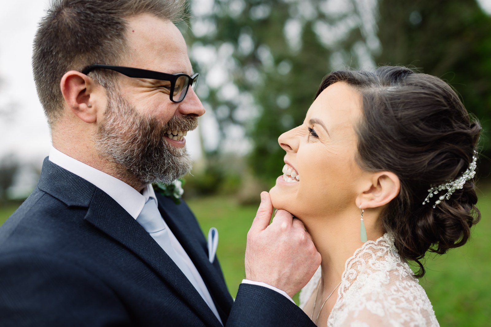 Close-up of the bride laughing as the groom cradles her cheek