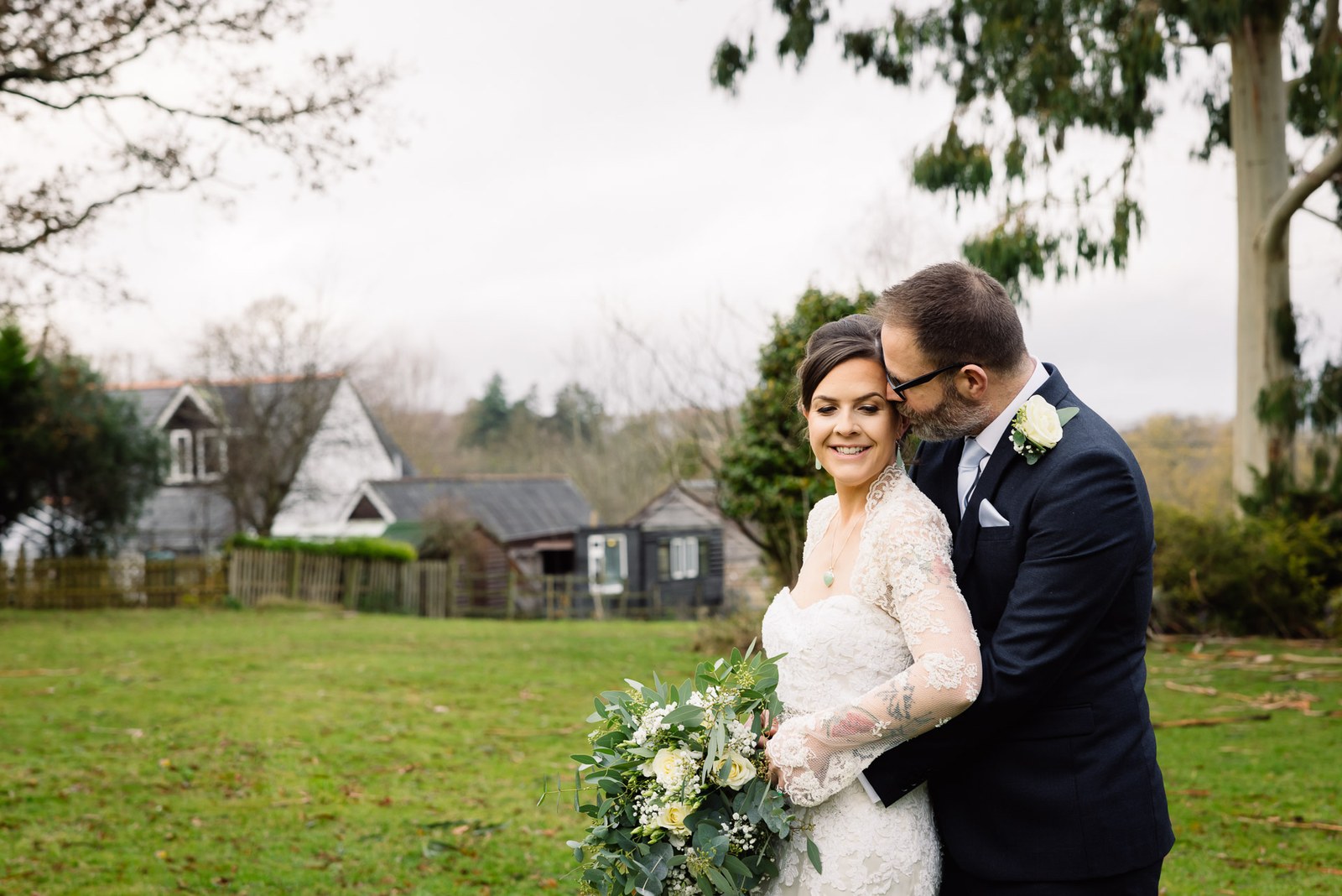 The couple embracing in the Woodlands Lodge Hotel grounds by a lodge building