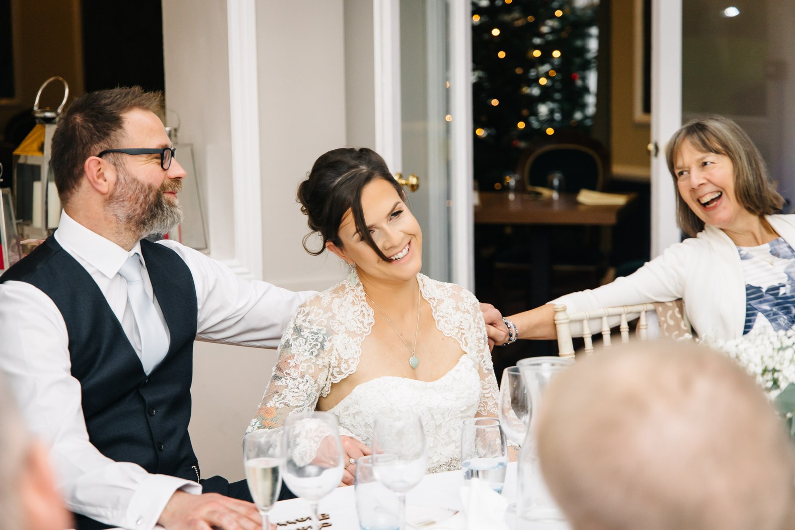The couple laughing with a guest during the wedding breakfast