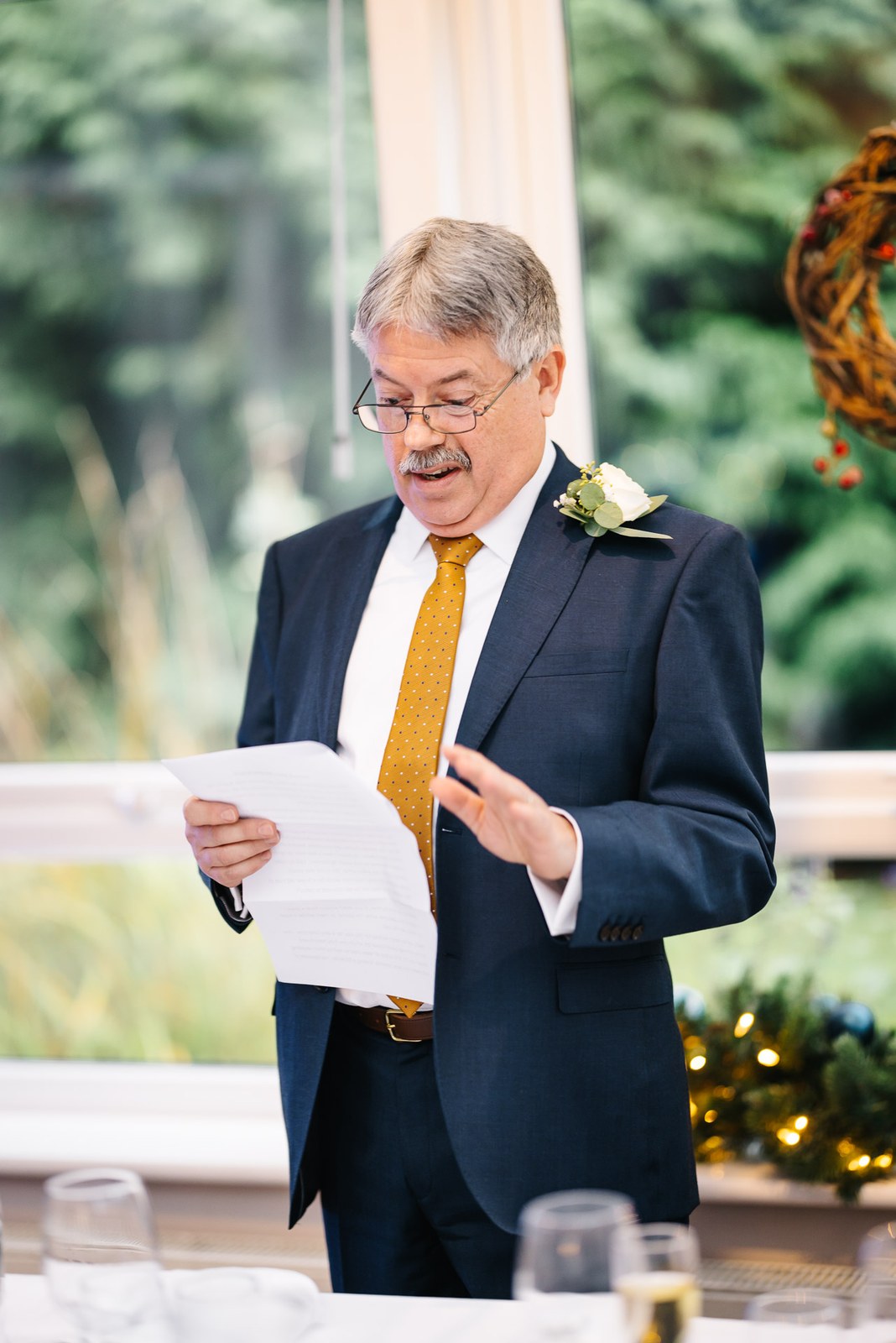 A guest delivering a speech from notes beside the window