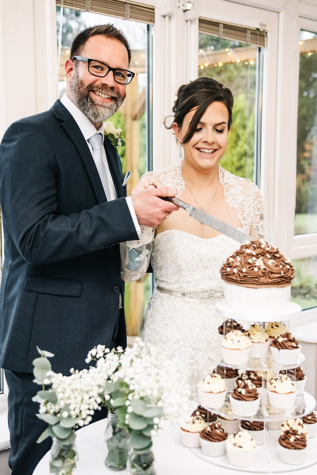The couple cutting their cupcake tower topped with a chocolate cake