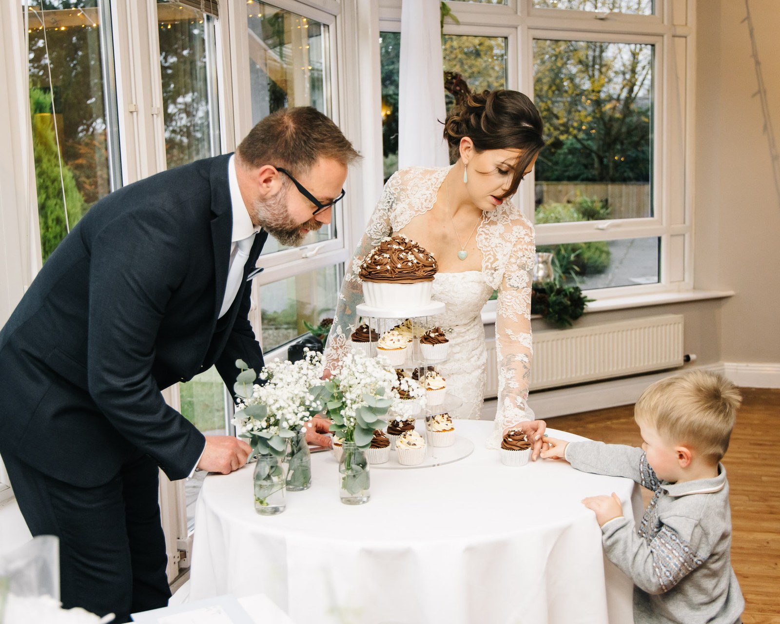 The couple choosing cupcakes as a young boy reaches up