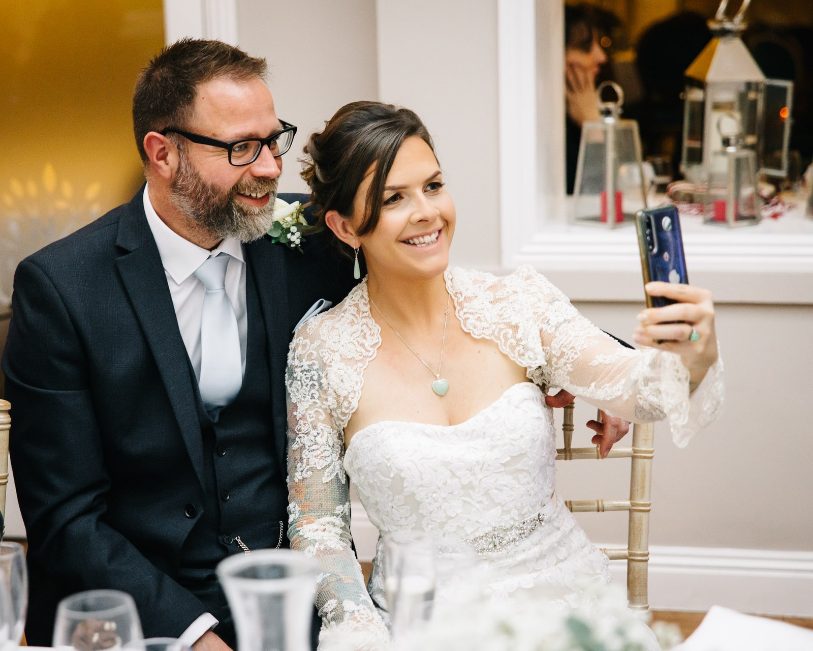 The couple taking a selfie together at the reception table