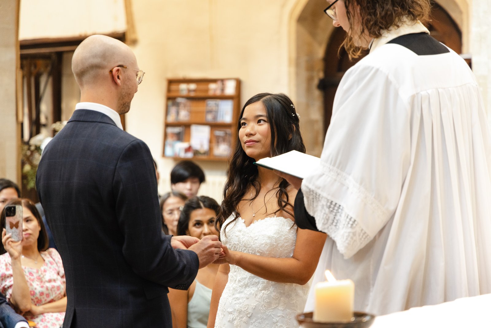 Bride and groom holding hands and smiling at each other during the church ceremony.
