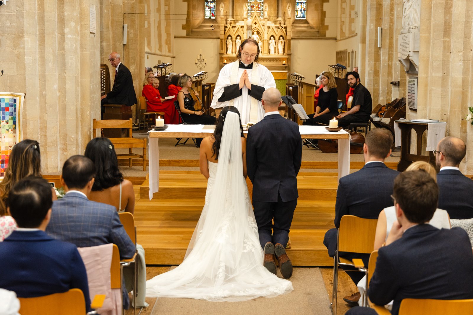Bride and groom at the altar beneath the gilded reredos, guests seated in the nave.