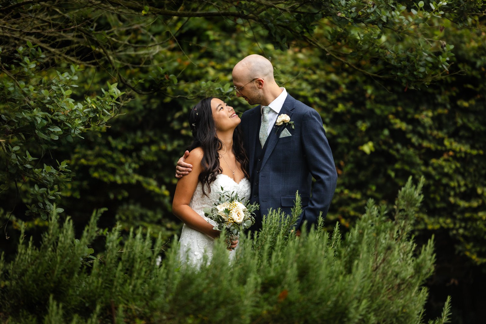 Bride and groom nose to nose beside the rosemary beds at Worton Hall.