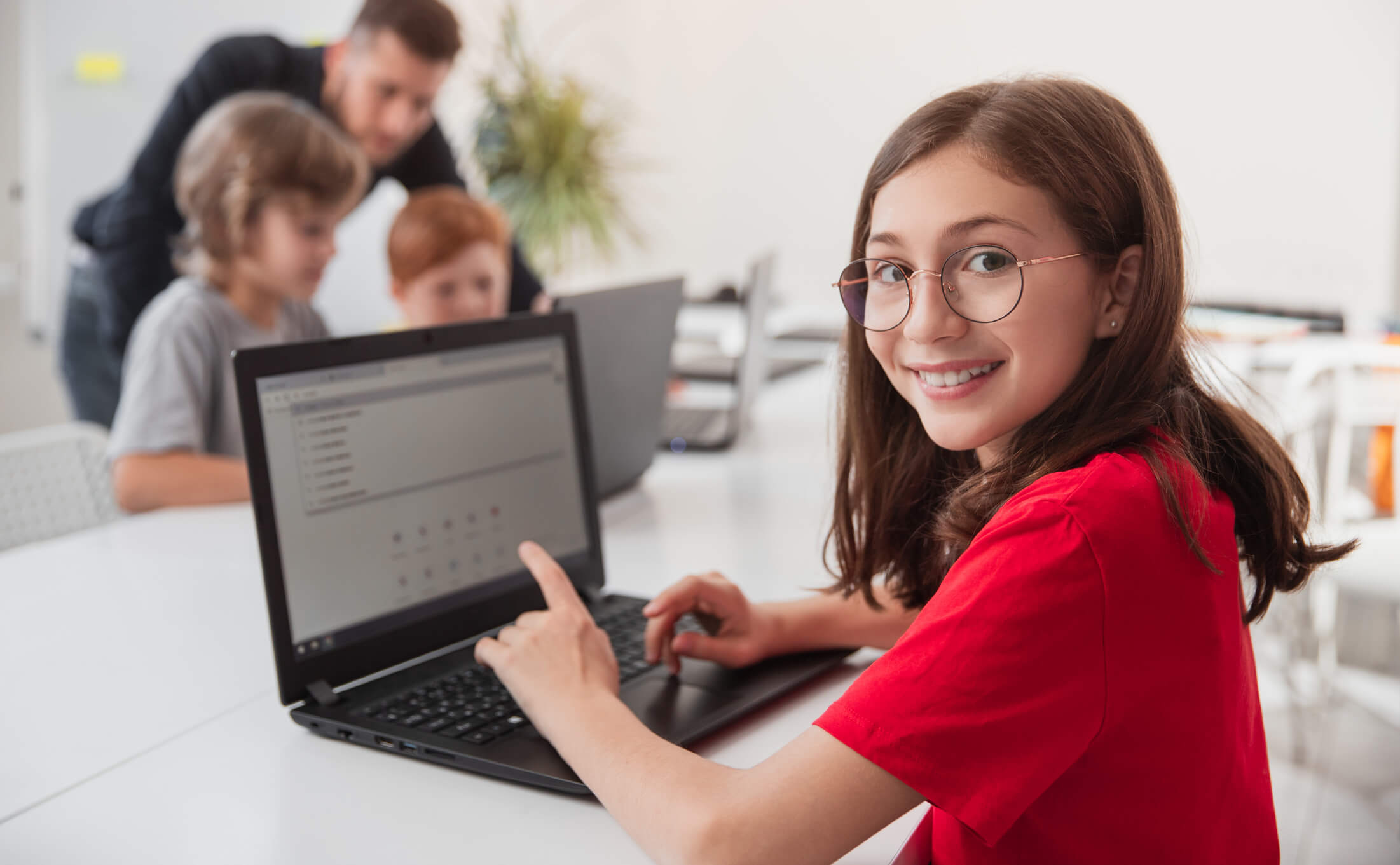 A kid in a red t-shirt using a laptop.