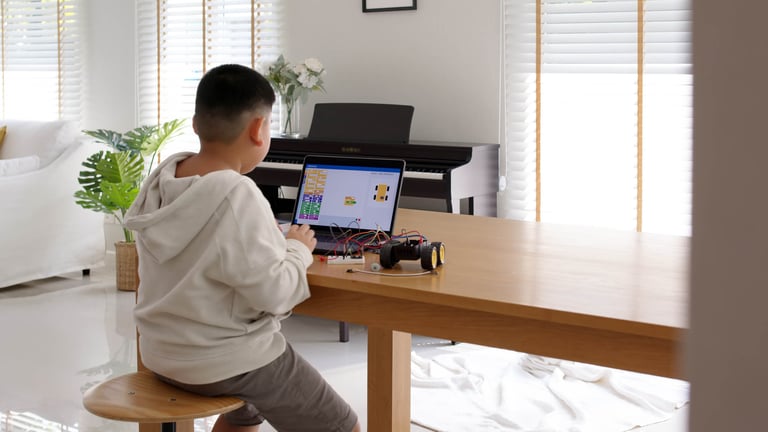 A young boy on a laptop doing block coding