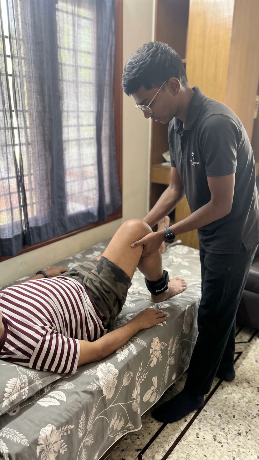 Physiotherapist assisting a senior with knee bending exercises on a bed
