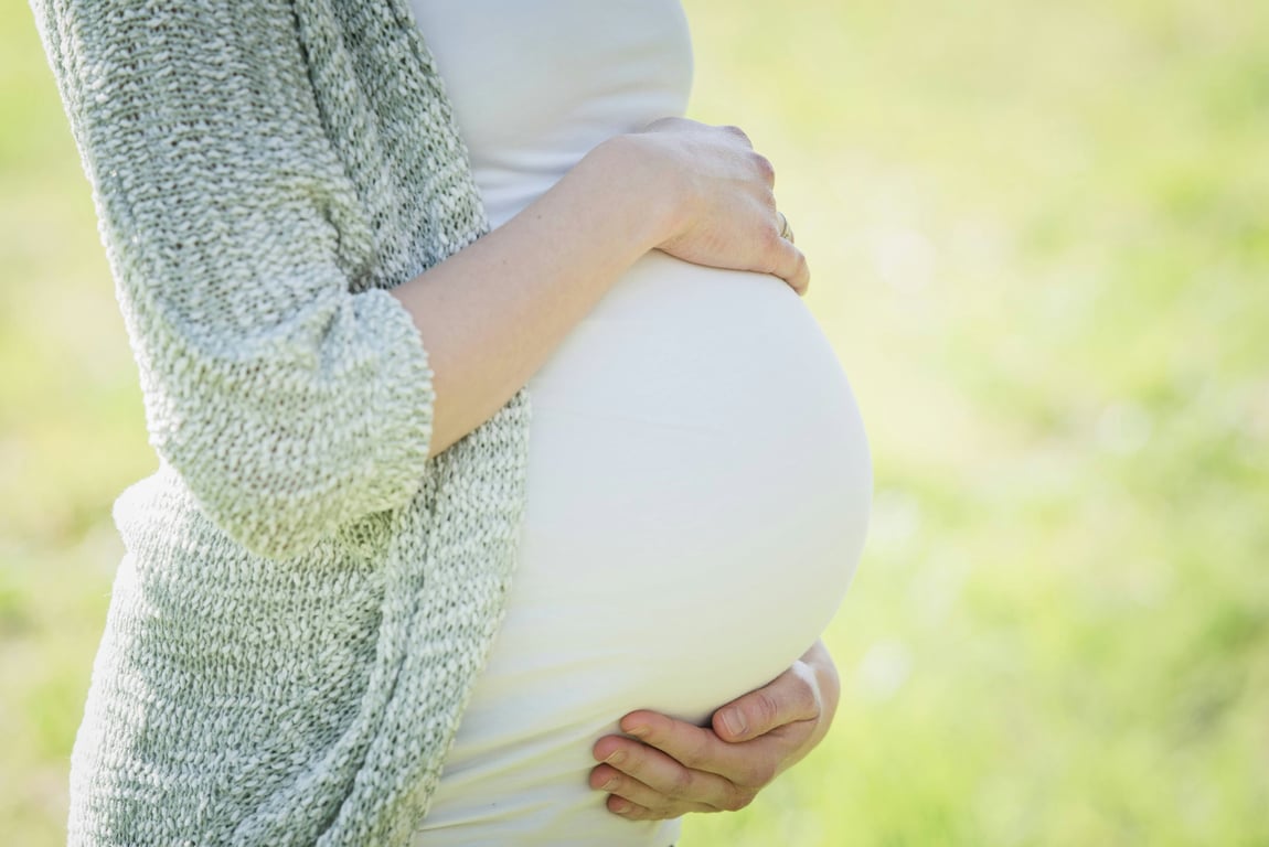 A lady who is pregnant, holding her belly.