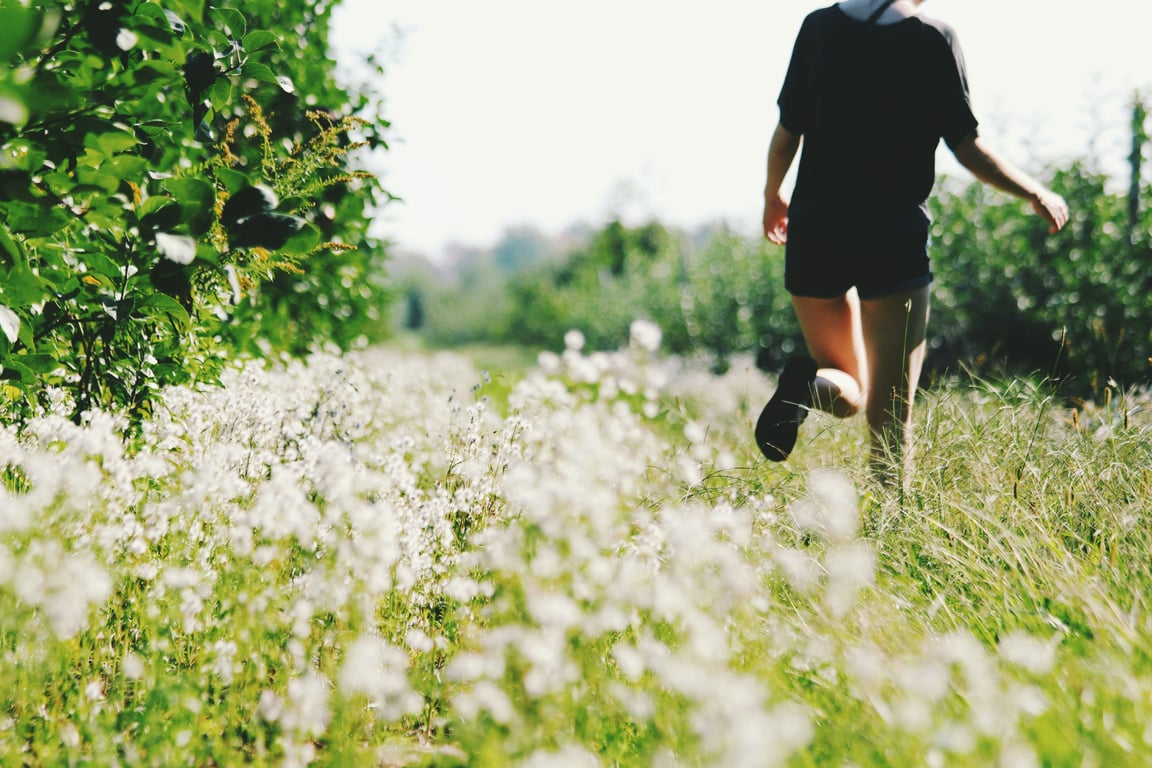 A youth running through a field of flowers