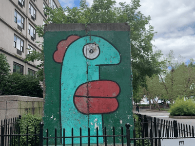 Colorful wall of the Berlin Wall, depicting a playful figure, located in a park, symbolizing freedom and art.