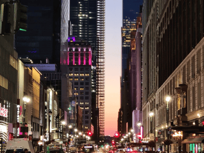 View of West 34th Street in New York, illuminated at dusk with modern buildings and colorful signs.
