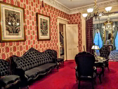 Interior of the living room of Theodore Roosevelt's birthplace, with black velvet furniture and vintage patterns on the walls.