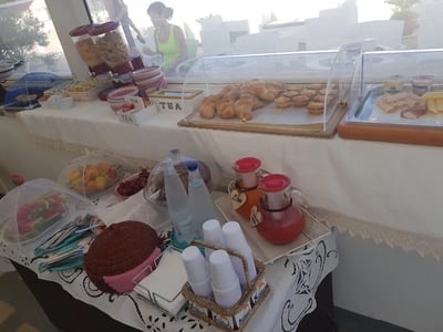 Buffet at Faro Bianco with fresh bread, fruits, drinks, and cereals, offering a delicious breakfast option.