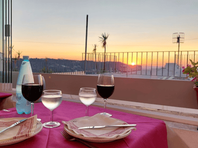 Sunset over the city of Spessite, with glasses of wine and water on an elegantly set table.