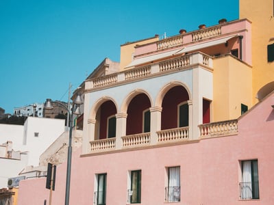 Colorful building in Castro Marina, with arched balconies and a welcoming Mediterranean atmosphere under a blue sky.