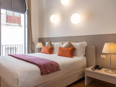 Modern room at Palazzo Indelli, with a comfortable bed, colorful cushions, and soft lighting, creating a warm atmosphere.