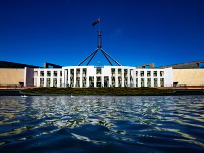 The Parliament building in Canberra, reflected in the water, a symbol of Australian democracy under a blue sky.