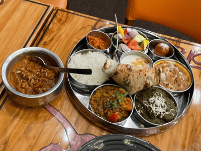 Traditional Indian meal with thali including rice, breads, curries, and fruits, served at a restaurant in Delhi 6.