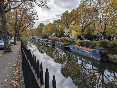 Regent's Canal with colorful barges and autumn leaves reflected on the calm water. A peaceful place in an urban setting.