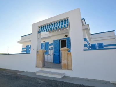 Welcoming entrance of the Mare Blu Apartments with blue shutters and a striped awning, evoking the coastal spirit of Case Vacanze Villani.