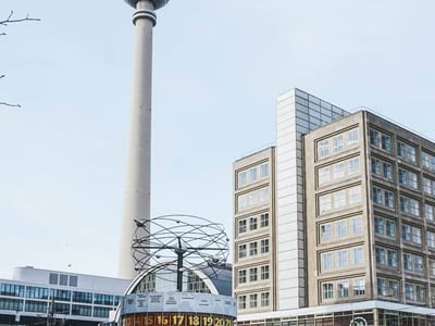 The famous Fernsehturm of Berlin stands majestically, surrounded by modern architecture and an iconic clock.