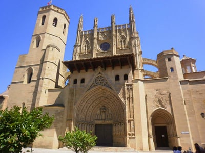 The impressive Gothic architecture of the cathedral of Huesca under a bright blue sky.