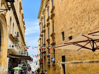 Rue animée de Gallipoli avec boutiques, drapeaux colorés et touristes profitant de l'ambiance locale en plein été.