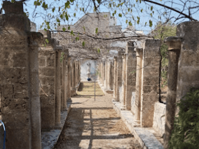 A pathway lined with ancient columns at the Castello Episcopio, evoking the history and architecture of the site.