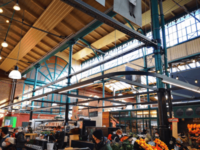 Interior of Markhalle Neun, a lively market with colorful stalls of fresh produce and impressive industrial architecture.