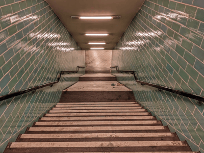 Stairs leading to the underground passages of the Berliner Unterwelt, with turquoise tiles and modern lighting.
